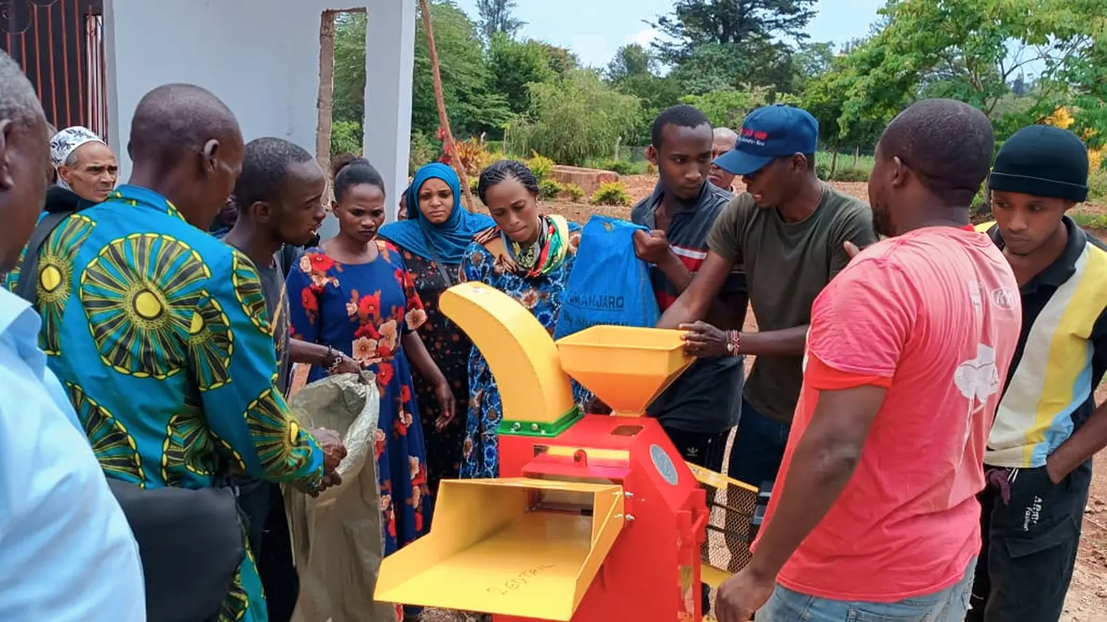Farmers observing a practical feed-processing demonstration
